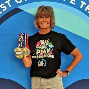 Susan Ingraham smiles and holds her medals at the 2022 National Senior Games.
